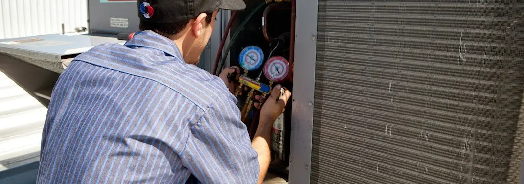 HVAC technician servicing a condenser unit in Bagley